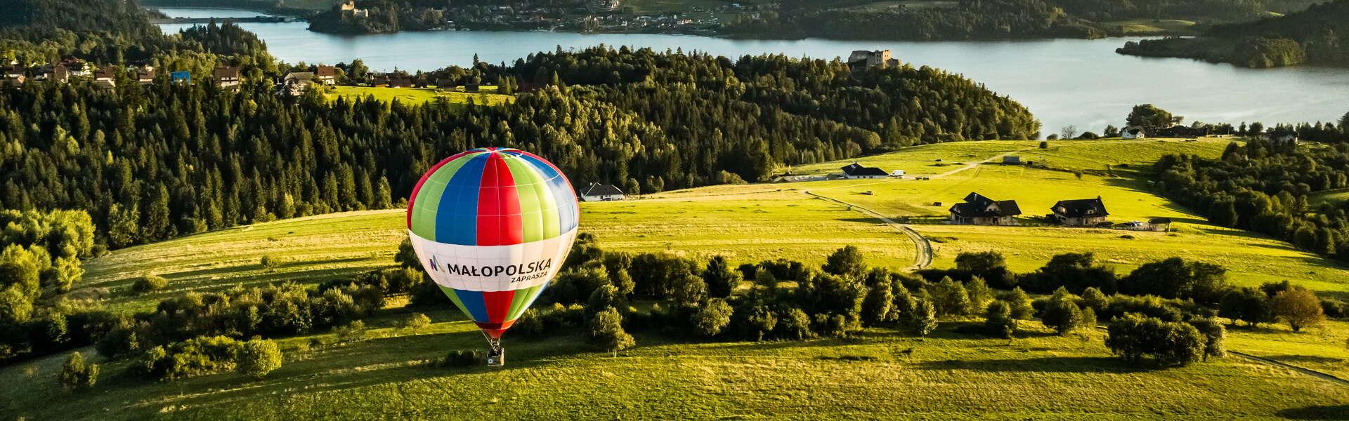 Widok na balon na ogrzane powietrze Małopolska unoszący się nad Czorsztynem. W tle widać jezioro Czorsztyńskie.